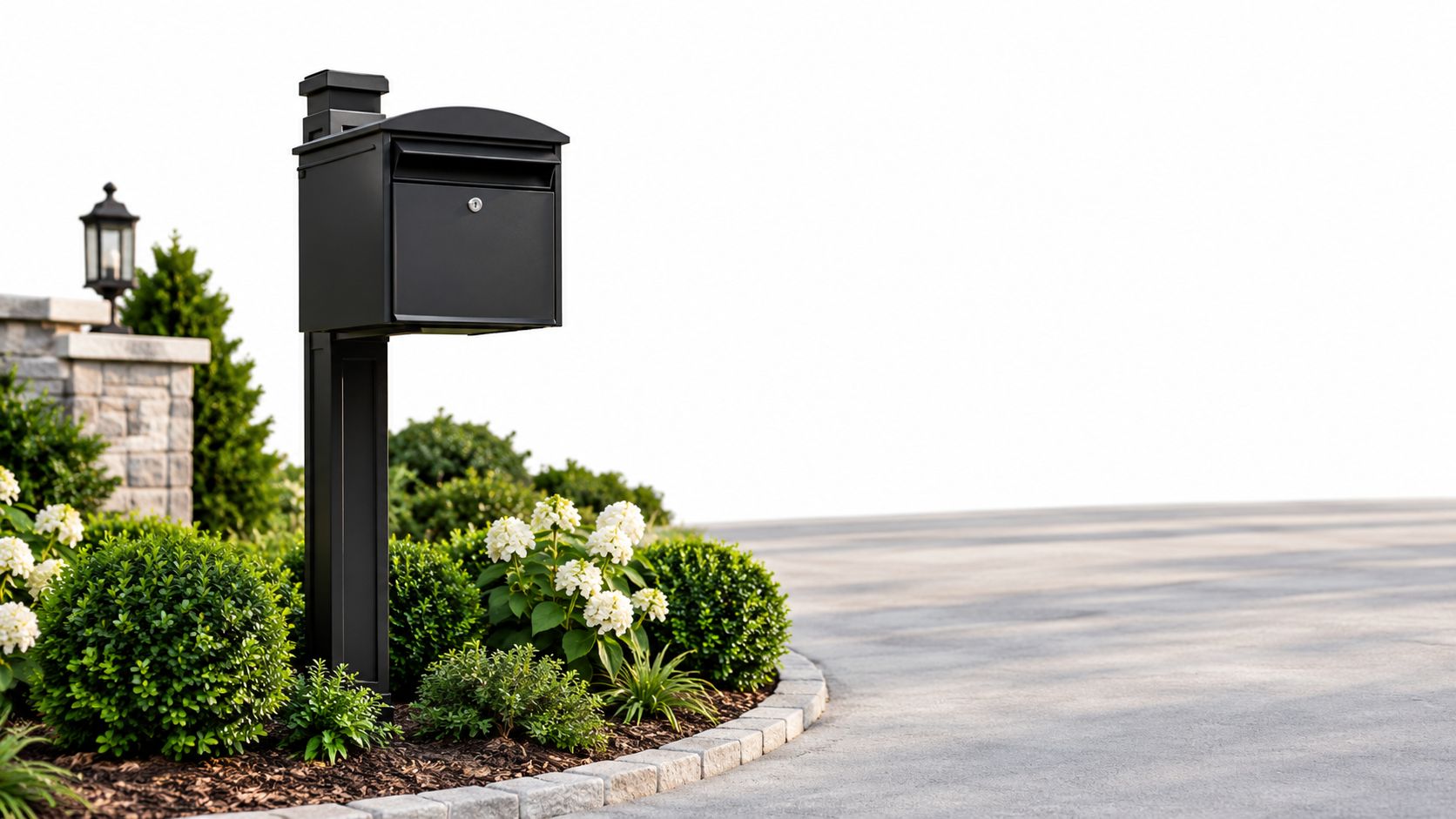 A sleek modern black locking mailbox installed in a landscaped garden next to a concrete driveway.